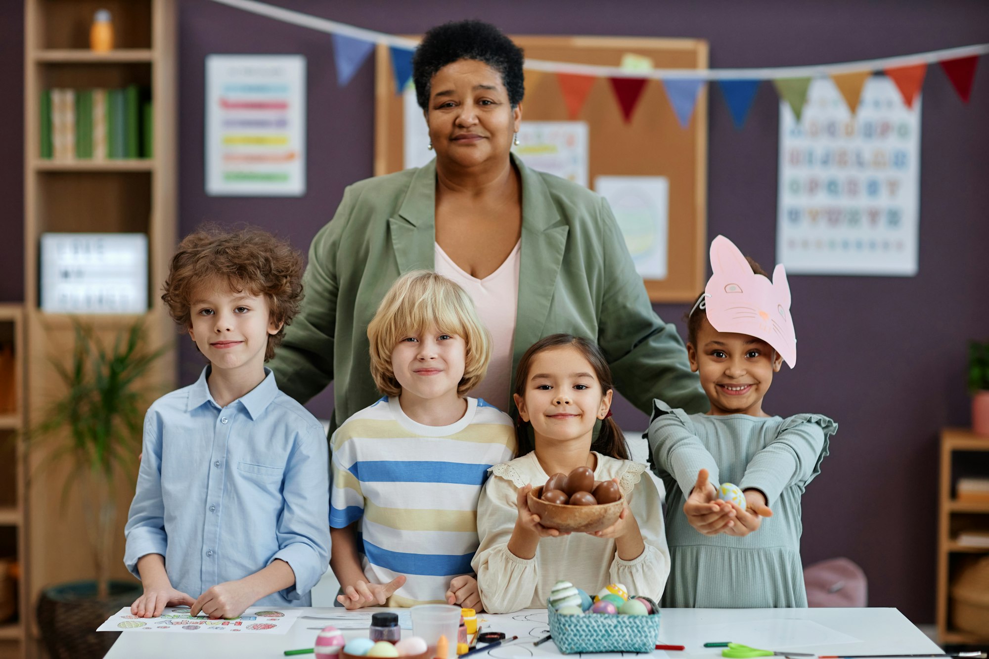 Female teacher posing with diverse group of children in preschool